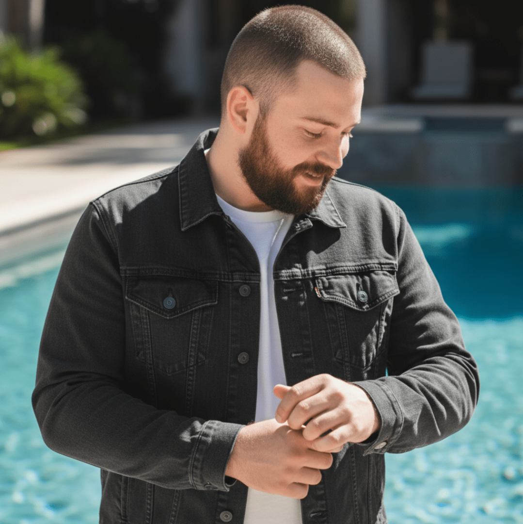 person wearing a black denim jacket outdoors near a pool showing jacket fit and front pocket placement