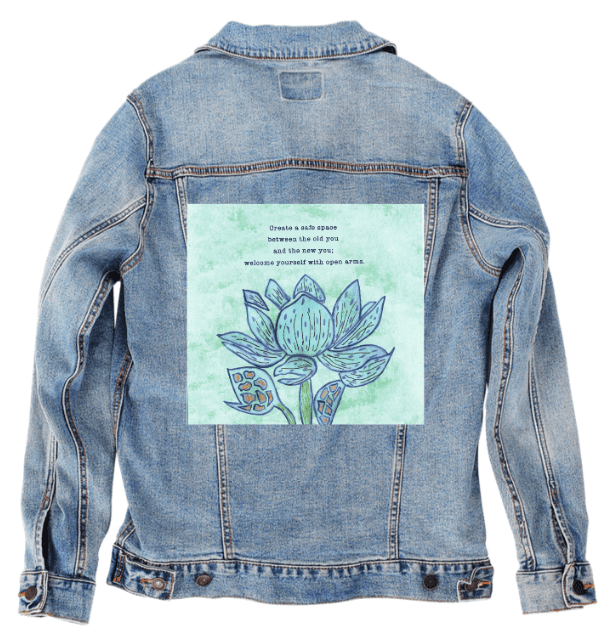 back view of a stonewash denim jacket displaying the artwork “Always Welcome Yourself” by Canvas & Quotations, showing a blue lotus flower beneath an inspirational quote on a soft green background. the artwork is digitally printed on the jacket’s back panel by DenimINK