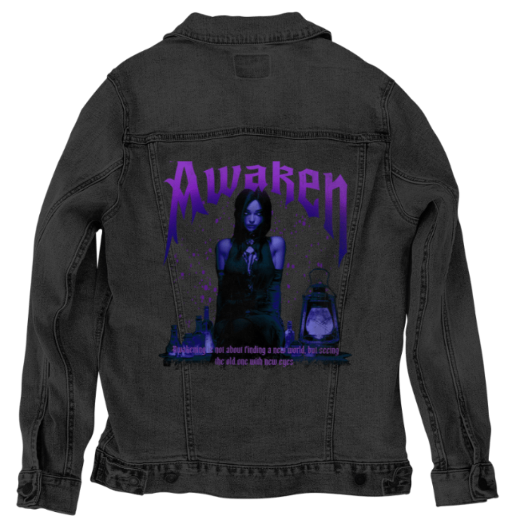back view of a black denim jacket featuring an eerie gothic scene with a seated figure, glowing purple lantern, and scattered potion bottles. dramatic purple lettering reads “Awaken” above the figure. the artwork “Awaken” by DeRouche Designs is digitally printed on the jacket’s back panel by DenimINK.