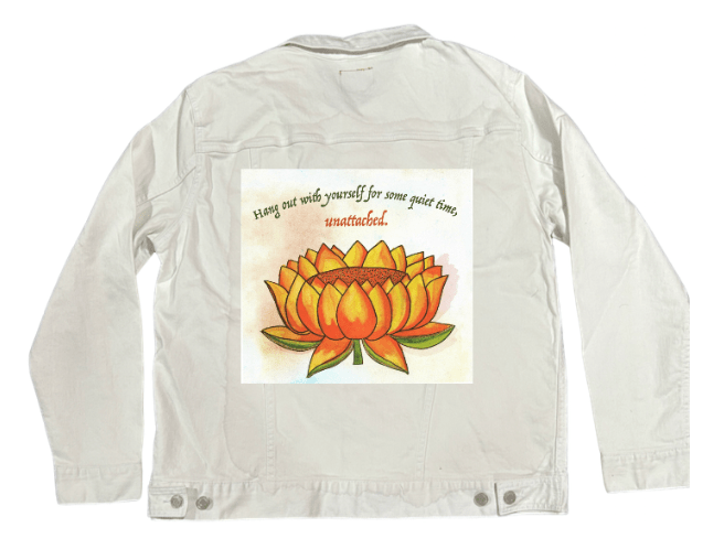 back view of a white denim jacket featuring the artwork “Be Unattached” by Canvas & Quotations, showing an orange lotus flower beneath the quote “Hang out with yourself for some quiet time, unattached.” the artwork is digitally printed on the jacket’s back panel by DenimINK