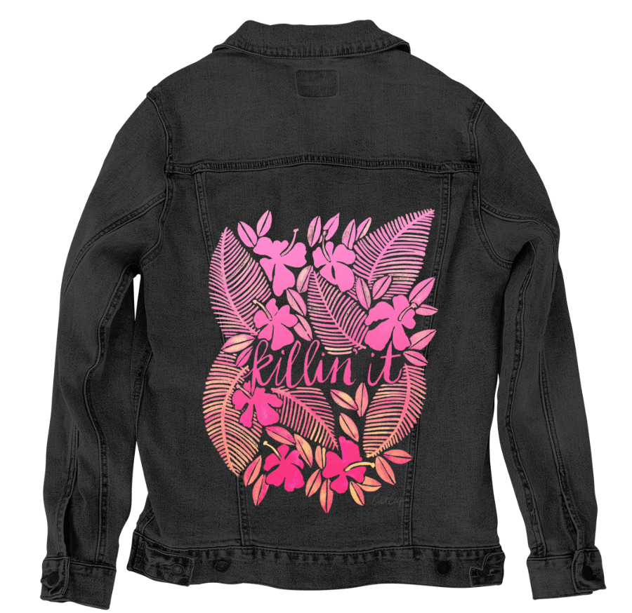 back view of a black denim jacket featuring the artwork “Killin' It” by CatCoq, digitally printed by DenimINK. the design includes the handwritten phrase “killin it” framed by overlapping tropical ferns & layered floral shapes in shades of coral, pink & blush. the bold colors pop vividly against the black denim, bringing vibrant contrast to the detailed botanical artwork.