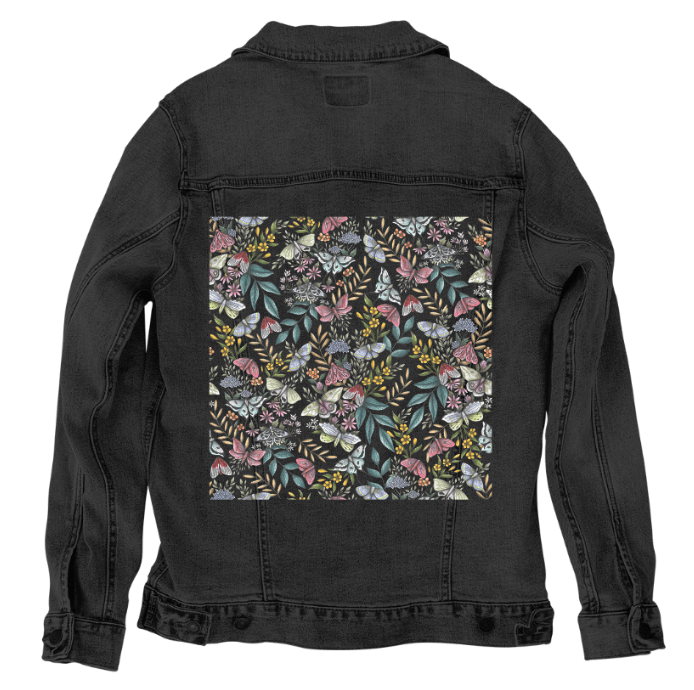 back view of a black denim jacket featuring the artwork “Midnight Garden” by Cecilia Battaini, a shadowy garden scene filled with hand-drawn moths in dusty pink, cream & pale blue, fluttering between curling branches, golden berries & fine leaves. the dark jacket fabric deepens the mood of the design, making it feel like a nighttime forest under starlight. the design is digitally printed on the jacket’s back panel by DenimINK.