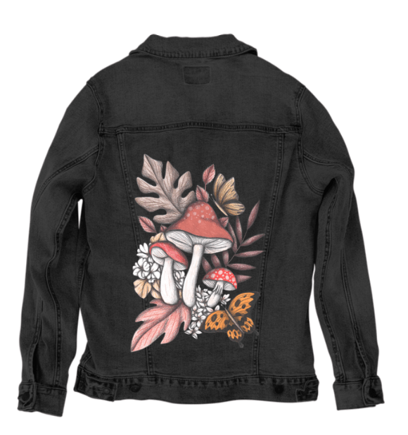 back view of a black denim jacket featuring a forest composition of red-capped mushrooms with textured stems, framed by faded oak leaves, pale florals, and a golden butterfly in mid-flight. the rich contrast of rusty orange and creamy white against the dark fabric gives the print a bold, enchanted feel. the artwork “Mushroom Magic 2” by Cecilia Battaini is digitally printed on the jacket’s back panel by DenimINK.