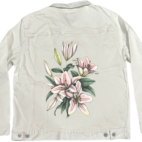 back view of a white denim jacket featuring a vertical floral artwork of soft pink lilies with subtle graphite texture & pale yellow-green leaf buds. the composition has a clean, light feeling that pairs smoothly with the crisp white denim. the artwork “Pink Lilies” by Cecilia Battaini is digitally printed on the jacket’s back panel by DenimINK.