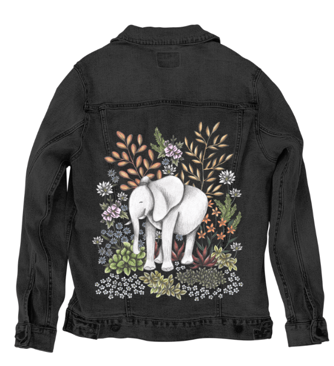 back view of a black denim jacket showcasing a printed artwork of a peaceful white elephant standing in a wild thicket of illustrated flowers, stems, leaves, & dried grasses. the moody background enhances the soft pencil shading & layered earthy tones. the artwork “Safari Elephant” by Cecilia Battaini is digitally printed on the jacket’s back panel by DenimINK.