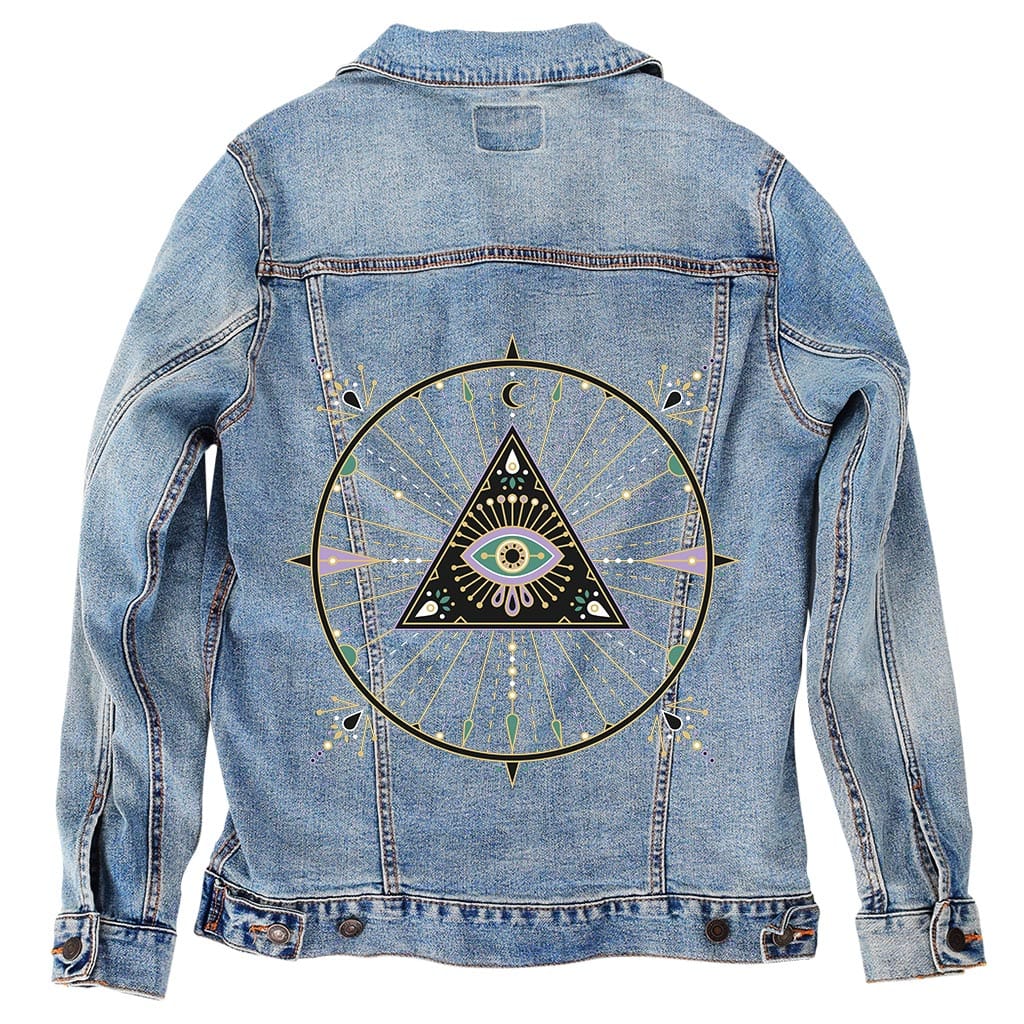 back view of a stonewashed denim jacket printed with the “Evil Eye Mandala” artwork by CatCoq. the design features a radiant triangle with an eye at its center, emitting geometric rays in gold, lavender, mint, & cream tones. surrounding the triangle is a detailed circular mandala with celestial & botanical flourishes. the washed denim softens the overall color contrast while preserving the crisp detail of the linework. printed by DenimINK.