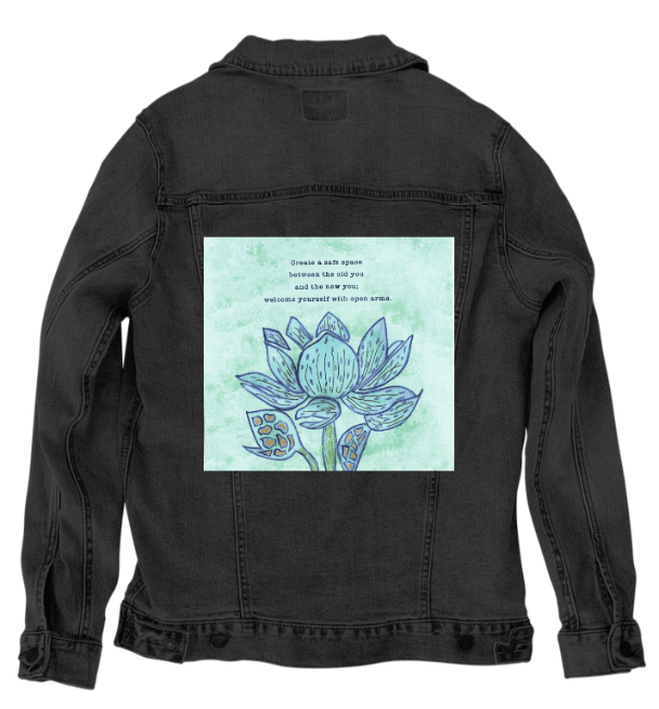 back view of a black denim jacket featuring the artwork “Always Welcome Yourself” by Canvas &amp; Quotations, with a blue lotus flower and the quote “Create a safe space between the old you and the new you; welcome yourself with open arms.” the artwork is digitally printed on the jacket’s back panel by DenimINK