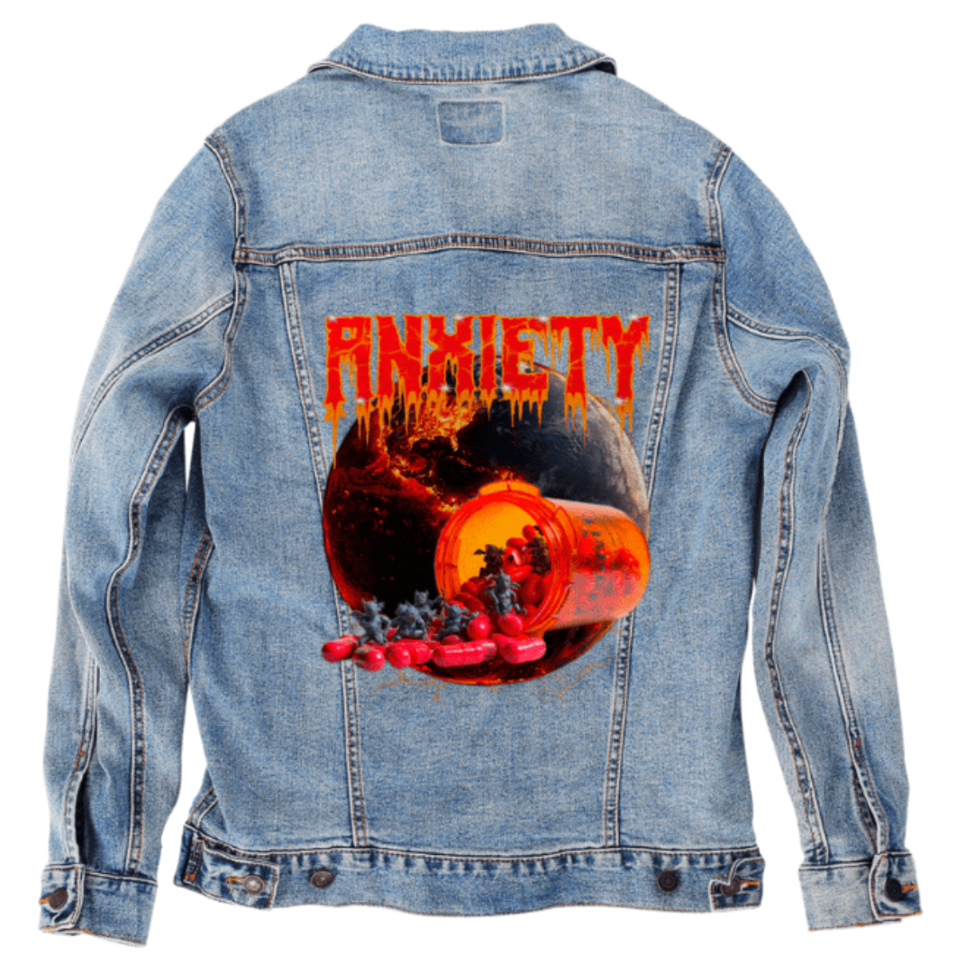 Flat lay of a stonewashed denim jacket with a mockup of the “Anxiety” artwork by DeRouche Designs printed on the back panel. The design shows a pill bottle spilling red capsules that release tiny demonic figures against the backdrop of a cracked molten planet. The artwork’s vivid reds, oranges, and blacks contrast sharply with the soft blue of the denim. Perfect for showcasing how bold horror-themed prints appear on lighter, distressed fabric. printed by DenimINK