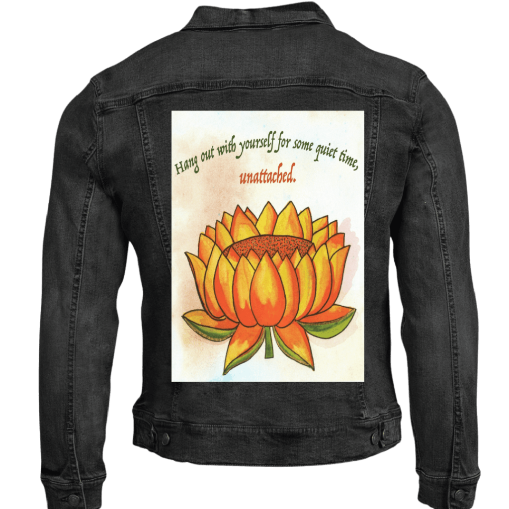 black denim jacket mockup featuring a warm-toned orange lotus flower on a textured background, paired with the quote “Hang out with yourself for some quiet time, unattached.” rendered in green and red script. this artwork is titled “Be Unattached” and created by Canvas &amp; Quotations (Monika Chugh and Alka Chopra) printed by DenimINK
