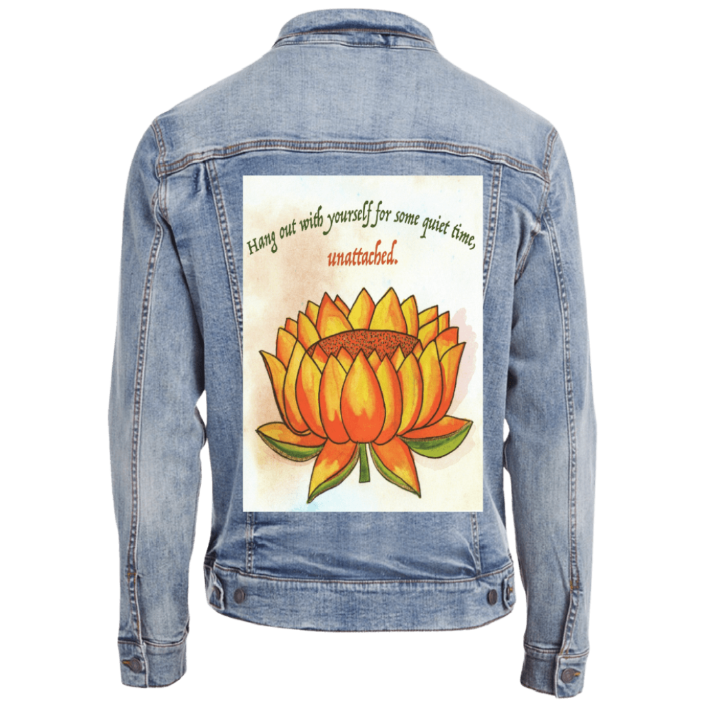 mockup on a stonewashed denim jacket eaturing a warm-toned orange lotus flower on a textured background, paired with the quote “Hang out with yourself for some quiet time, unattached.” rendered in green and red script. this artwork is titled “Be Unattached” and created by Canvas &amp; Quotations (Monika Chugh and Alka Chopra) printed by DenimINK