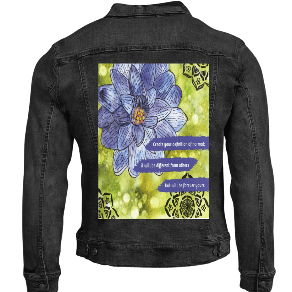 black denim jacket mockup featuring a blue and purple lotus flower on a textured green background, paired with the quote “Create your definition of normal; it will be different from others but will be forever yours.” decorative black mandala-style motifs appear in the corners. this artwork is titled “Be Your Normal Self” and created by Canvas &amp; Quotations (Monika Chugh and Alka Chopra), printed by DenimINK