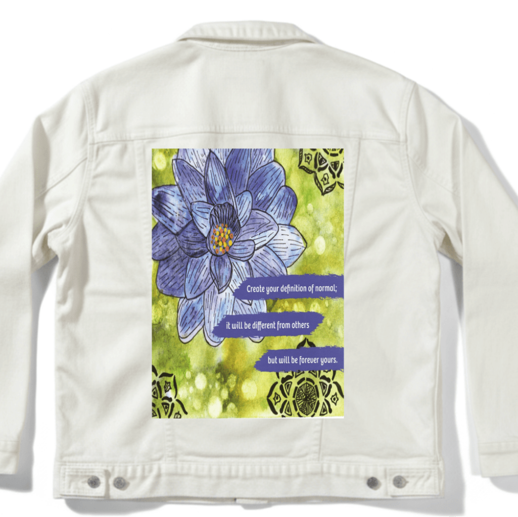 white denim jacket with mockup featuring a blue and purple lotus flower on a textured green background, paired with the quote “Create your definition of normal; it will be different from others but will be forever yours.” decorative black mandala-style motifs appear in the corners. this artwork is titled “Be Your Normal Self” and created by Canvas &amp; Quotations (Monika Chugh and Alka Chopra), printed by DenimINK