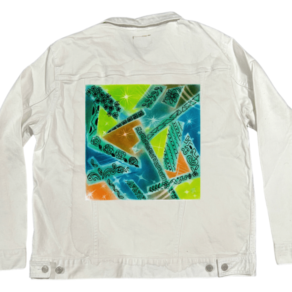 back view of a white denim jacket featuring the artwork “Abstract Magic” by Canvas &amp; Quotations (Monika Chugh and Alka Chopra), showing bright overlapping shapes in green, blue, orange, and yellow accented with starbursts, spray-paint textures, and hand-drawn floral, leaf, and geometric line elements throughout the composition. the artwork is digitally printed on the jacket’s back panel by DenimINK.
