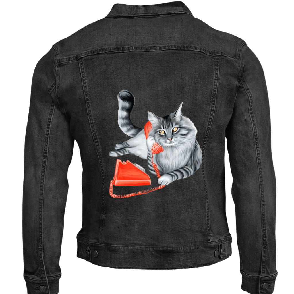 Mock up of of a fluffy gray long-haired cat reclining with its tail curled upward, holding a bright red vintage telephone receiver to its ear Digitally printed by DenimINK on a unisex black denim jacket.  the cat’s fur is rendered in layered charcoal &amp; silver tones with fine whisker lines and golden-yellow eyes gazing forward. a matching red phone base &amp; coiled cord rest below. titled “Cat on the Phone” &amp; created by Amélie Legault 