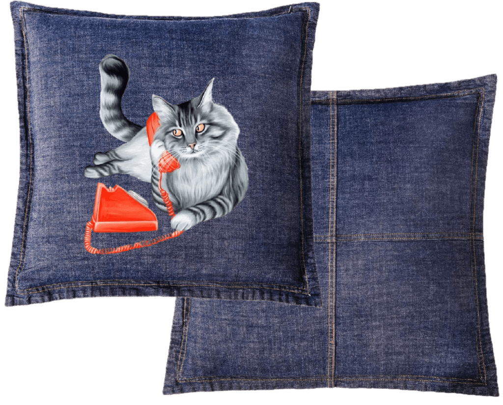 Mock up of a fluffy gray long-haired cat reclining with its tail curled upward, holding a bright red vintage telephone receiver to its ear Digitally printed by DenimINK on a Classic blue denim throw pillow.  gazing forward. a matching red phone base and coiled cord rest below. titled “Cat on the Phone” and created by Amélie Legault 