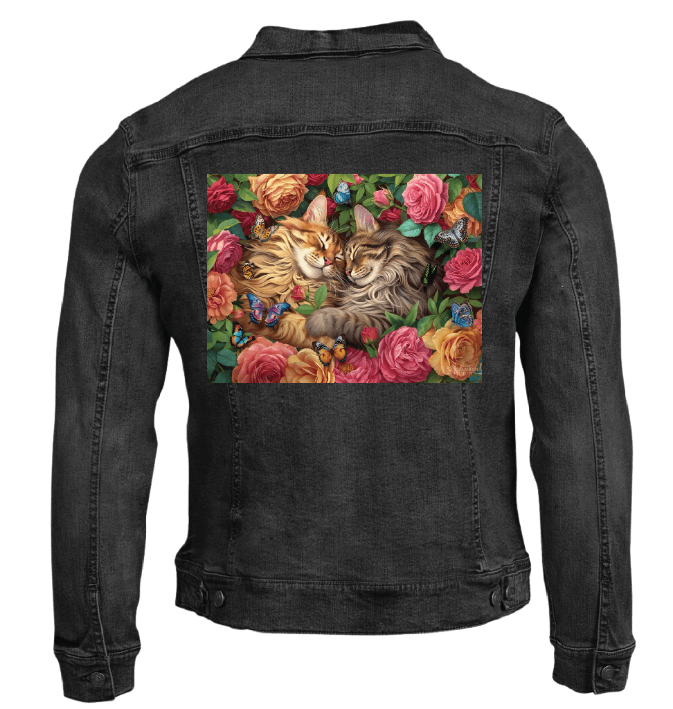 back view of a black denim jacket featuring the artwork “Cats in Love” by Brigid Ashwood, printed centered on the back panel. the artwork depicts two long-haired cats resting cheek to cheek among roses, green foliage, and small colorful butterflies. the warm floral colors contrast clearly against the dark denim. digitally printed by DenimINK.