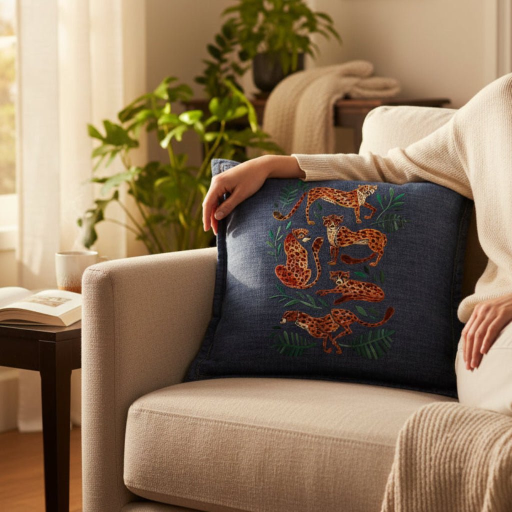 Person holding a decorative pillow with floral patterns on a beige armchair in a cozy living room. cheetah-Collection-by-CatCoq-throw-pillow-lifestyle-shot