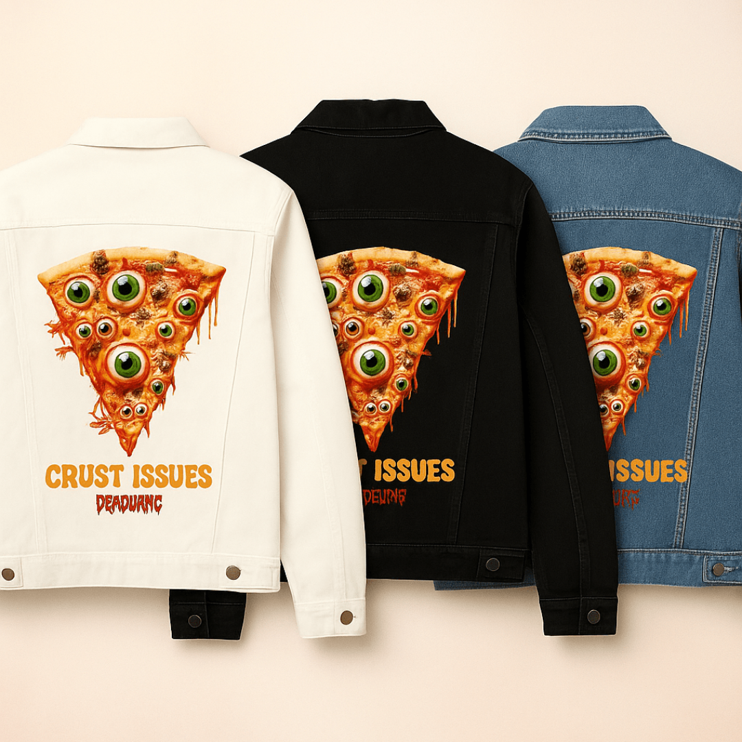 Flat lay of three denim jackets arranged side by side against a pale background — one in white, one in black, and one in stonewashed blue. Each jacket features the same oversized back print: the "Crust Issues" artwork by DeRouche Designs, showing a melted slice of pizza embedded with realistic eyeballs and gory faces. The layout is ideal for comparing print vibrancy across different denim shades, highlighting the bold oranges, greens, and reds of the design.