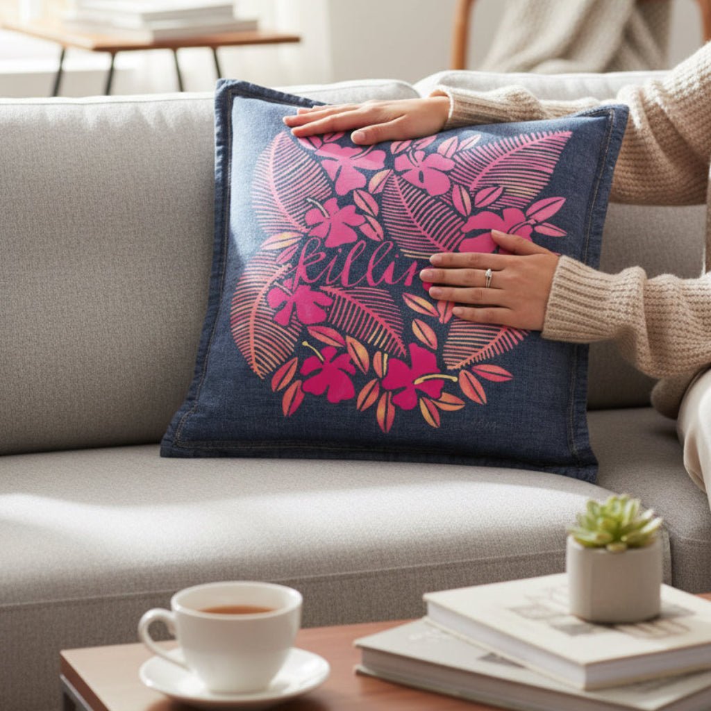Person holding a decorative pillow with floral pattern on a couch in a living room.  killin-it-by-CatCoq-denim-throw-pillow-lifestyle-sho
