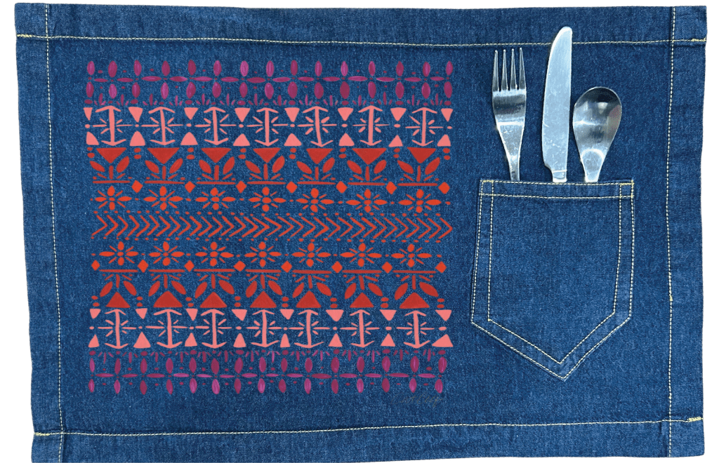 Denim placemat with a cutlery pocket with a vertically aligned Scandinavian folk pattern "Norwegian Pattern" by CatCoq made of repeating geometric rows including tulip shapes, arrows, diamonds, snowflakes &amp; stylized trees. the hand-painted elements fade from deep violet at the top to coral &amp; rust red toward the center, then shift to pink &amp; purple again. printed by DenimINK