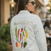 Short looping video showing a finished white DenimINK custom denim jacket worn over a white t-shirt, featuring bold red hand-painted text reading “HOT STUFF” created by thearticsoul. The jacket is shown in motion as the wearer subtly shifts, allowing the painted artwork to catch the light and demonstrate how the custom design moves naturally when worn, highlighting the scale, placement, and texture of the artwork on the back of the jacket.