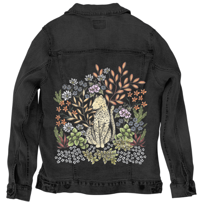 back view of a black denim jacket mockup featuring a bold forest scene with a golden leopard sitting upright among stylized jungle flora. vivid ivory flowers, coppery leaves, sage succulents &amp; tiny pale blossoms emerge in striking contrast against the deep black fabric. the overall design evokes a rich twilight mood. the artwork “Safari Leopard” by Cecilia Battaini is digitally printed on the jacket’s back panel by DenimINK.