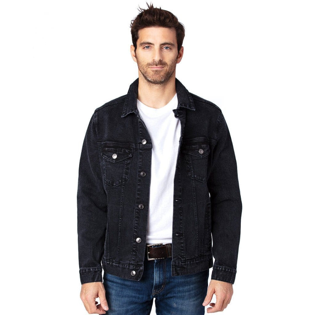 front view of a  model standing in a studio wearing a open plain black unisex retail-fit style classic-cut denim jacket showing buttons, front pockets, stitching and clean print panel with no artwork