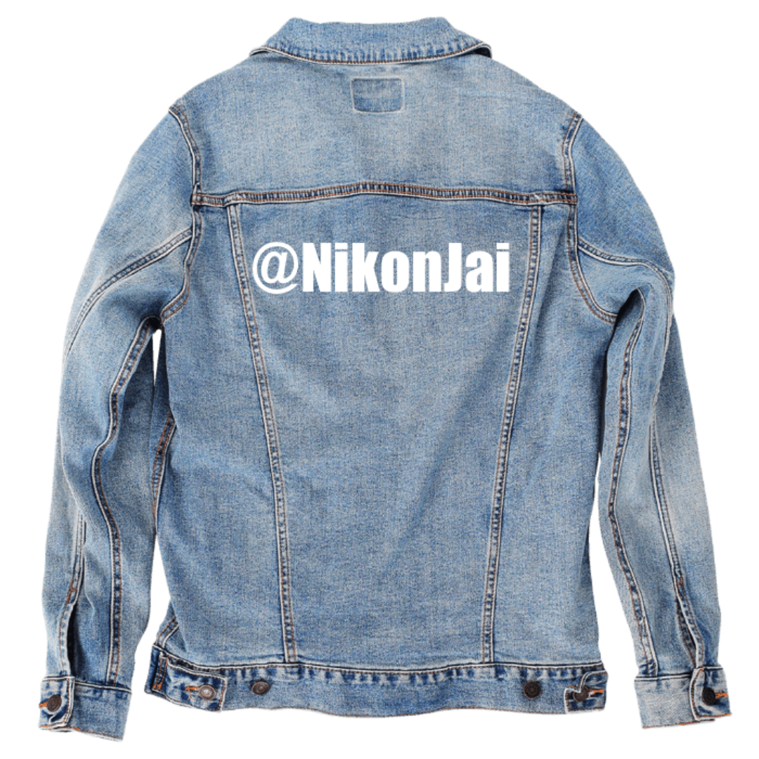 Customer designed custom denim jacket (M stonewash) featuring bold white lettering across the upper back that reads “@NikonJai” in a clean, modern font. The bright text stands out sharply against the textured, faded blue denim, creating a personalized statement piece that highlights a social media handle or nickname with crisp, high-contrast styling, printed on denim jacket by DenimINK.