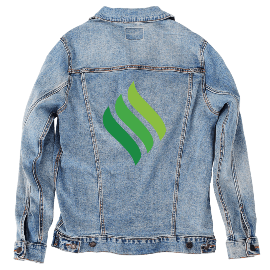 Customer designed custom denim jacket (S stonewash) featuring a bold abstract symbol printed on the back, composed of three curved flame- or leaf-shaped forms arranged side-by-side in varying shades of green. The smooth gradient colors and flowing shapes give the design a clean, modern, eco-inspired aesthetic that contrasts strikingly with the textured, faded blue denim, creating a simple yet eye-catching graphic, printed on denim jacket by DenimINK.