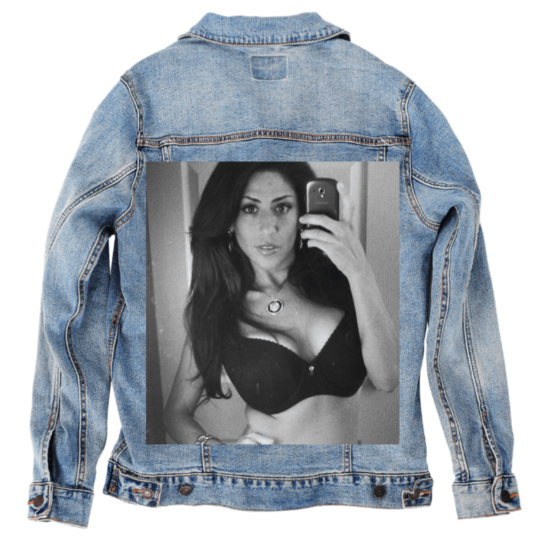 Customer designed custom denim jacket (XL stonewash) featuring a black-and-white mirror selfie printed large on the back. The portrait shows a woman standing indoors, holding a phone toward the mirror, her long dark hair falling over her shoulders. She wears a fitted top with a pendant necklace resting at her collarbone. Soft highlights and shadows shape her face and upper body, while the blurred room behind her provides gentle contrast against the rugged stonewash denim, printed on denim jacket by DenimINK
