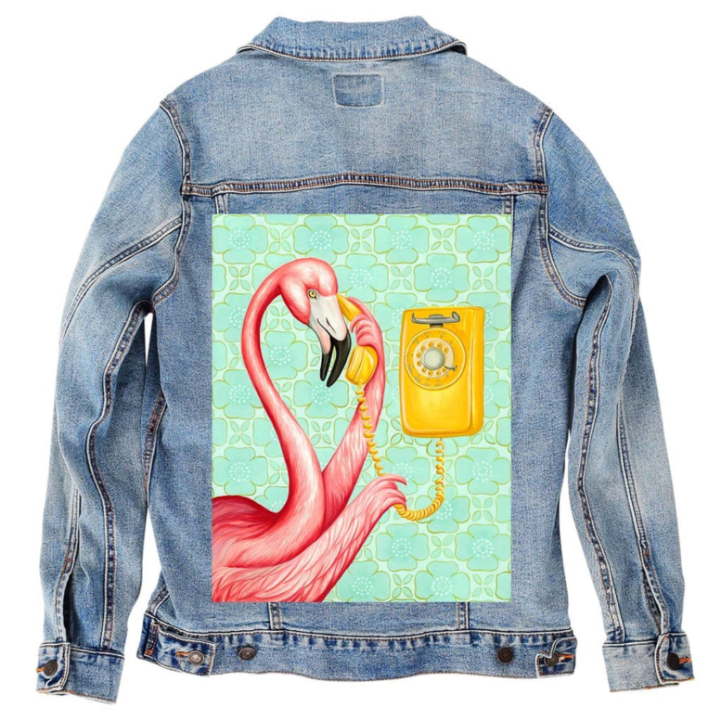 back view of a stonewash denim jacket featuring the artwork “Pink Flamingo on the Phone 2” by Amélie Legault, showing a pink flamingo holding a yellow rotary telephone handset against a teal patterned background. the artwork is digitally printed on the jacket’s back panel by DenimINK